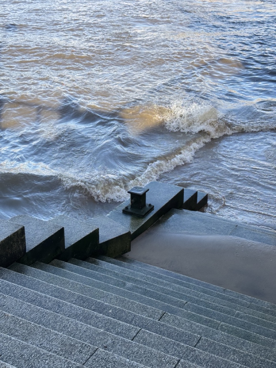 Photograph of waves lapping at the base of a stone staircase that disappears into the Thames